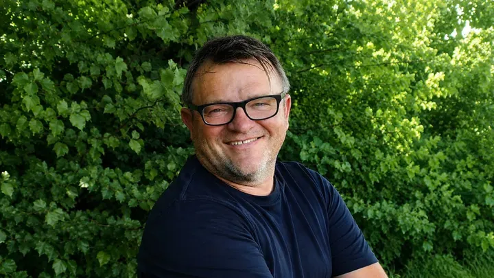 Ein Mann mit Brille lächelt freundlich in die Kamera.